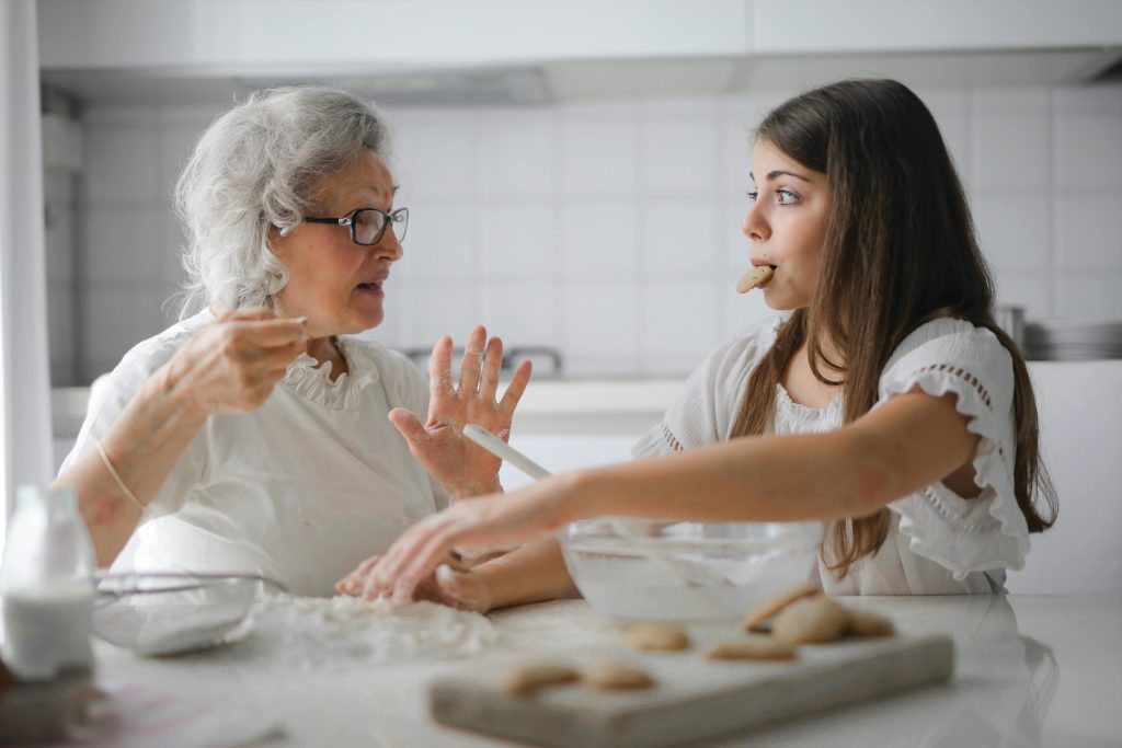 pexels-photo-3768146-3768146 Calm senior woman and teenage girl in casual clothes looking at each other and talking while eating cookies and cooking pastry in contemporary kitchen at home
